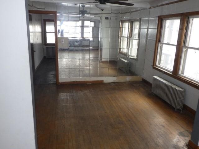 unfurnished room with dark hardwood / wood-style flooring, radiator heating unit, and ceiling fan