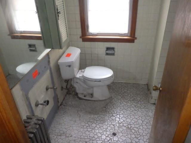 bathroom featuring toilet, radiator, and tile walls