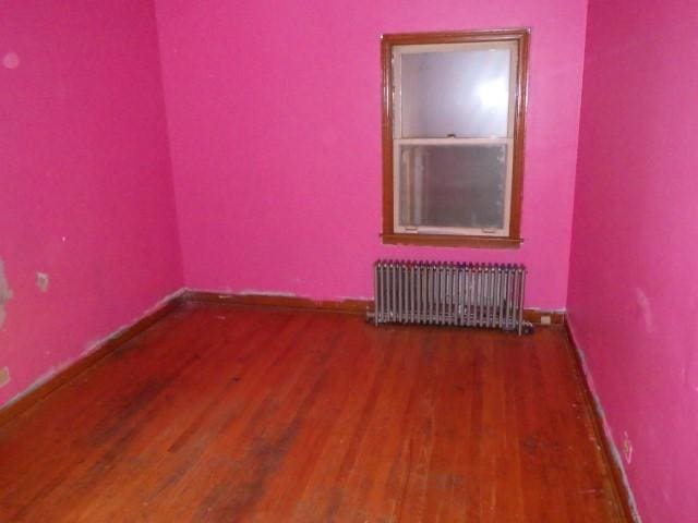 unfurnished room featuring radiator heating unit and dark hardwood / wood-style floors