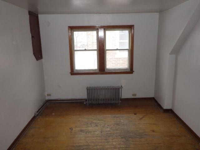 additional living space featuring hardwood / wood-style floors and radiator heating unit