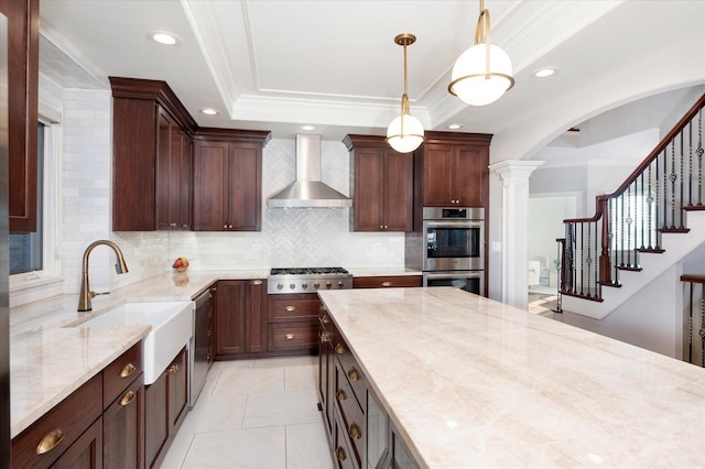 kitchen featuring decorative backsplash, appliances with stainless steel finishes, light stone counters, sink, and wall chimney range hood