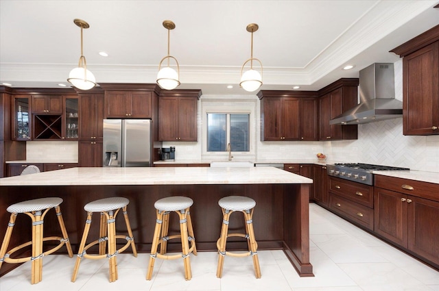 kitchen featuring light stone counters, a spacious island, wall chimney range hood, and stainless steel appliances