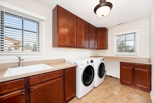 laundry room featuring washing machine and clothes dryer, light tile patterned flooring, cabinets, and sink