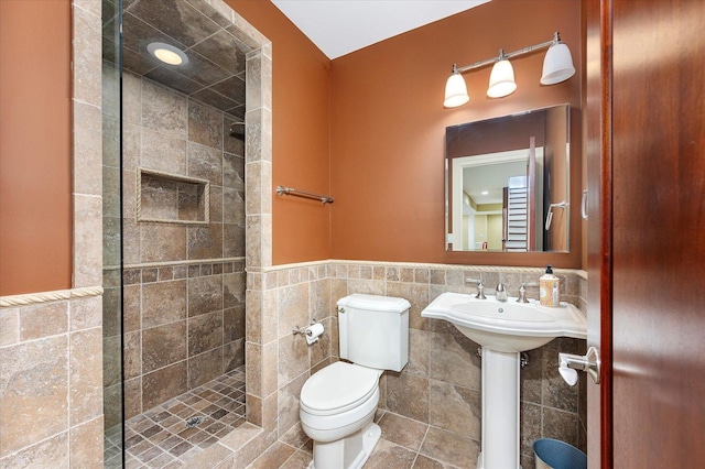 bathroom with toilet, tile walls, and tiled shower