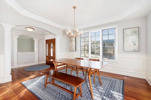 dining area with ornate columns, a chandelier, dark hardwood / wood-style floors, and ornamental molding