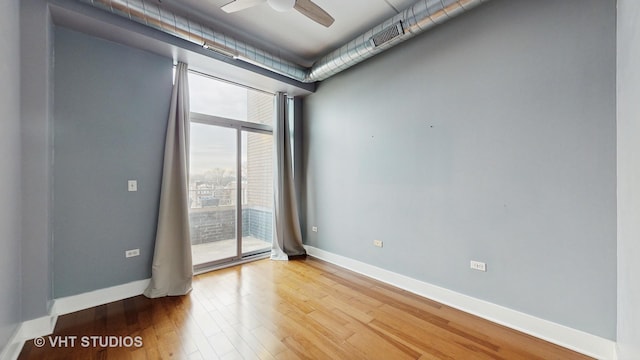 spare room with hardwood / wood-style flooring, expansive windows, and ceiling fan