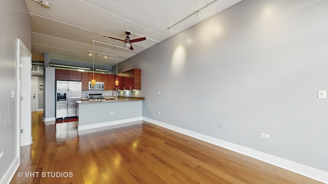 kitchen with track lighting, stainless steel appliances, sink, kitchen peninsula, and ceiling fan