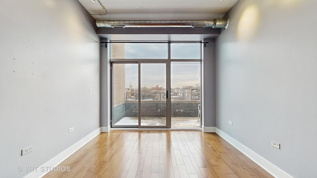 spare room featuring light wood-type flooring, a wealth of natural light, and expansive windows