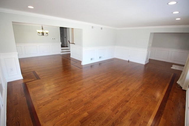 unfurnished room with a notable chandelier, crown molding, and dark wood-type flooring