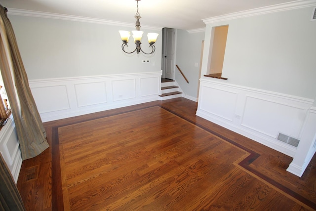 unfurnished dining area with dark wood-type flooring, ornamental molding, and a chandelier