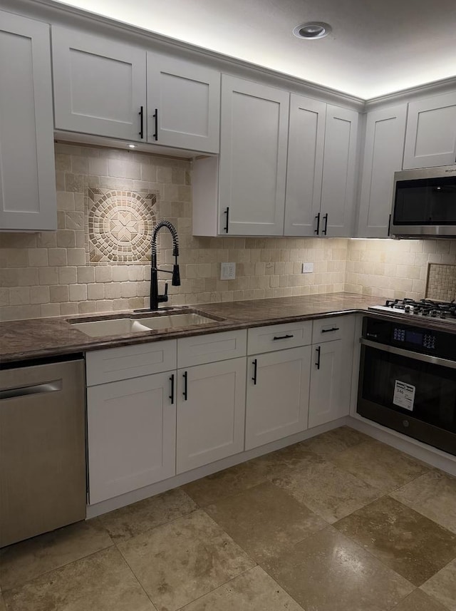 kitchen with sink, backsplash, white cabinets, and appliances with stainless steel finishes