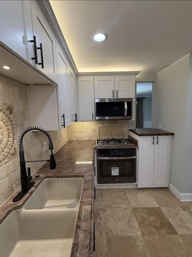 kitchen with sink, decorative backsplash, white cabinets, and range