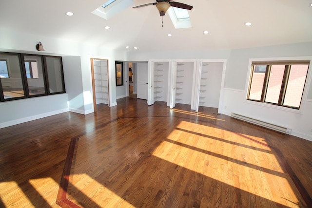 unfurnished living room featuring ceiling fan, a baseboard radiator, dark hardwood / wood-style floors, and vaulted ceiling with skylight