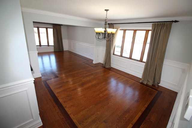 unfurnished dining area featuring crown molding, dark hardwood / wood-style floors, and a chandelier