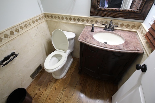 bathroom featuring hardwood / wood-style flooring, vanity, toilet, and tile walls