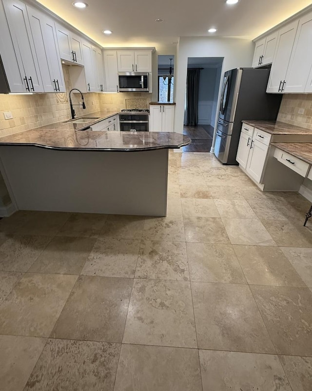 kitchen featuring white cabinetry, sink, stainless steel appliances, and kitchen peninsula