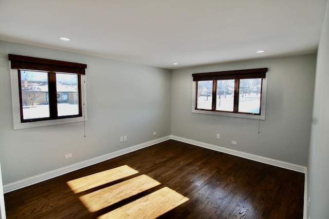 empty room featuring plenty of natural light and dark hardwood / wood-style floors