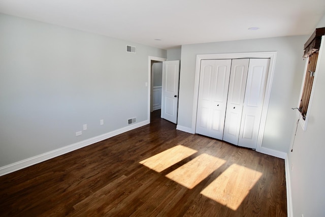 unfurnished bedroom with dark hardwood / wood-style flooring and a closet