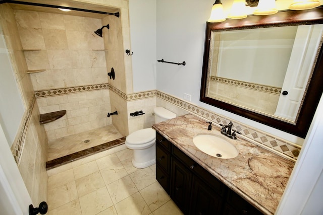 bathroom with vanity, toilet, tile walls, and a tile shower