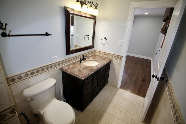 bathroom featuring vanity, toilet, and tile walls