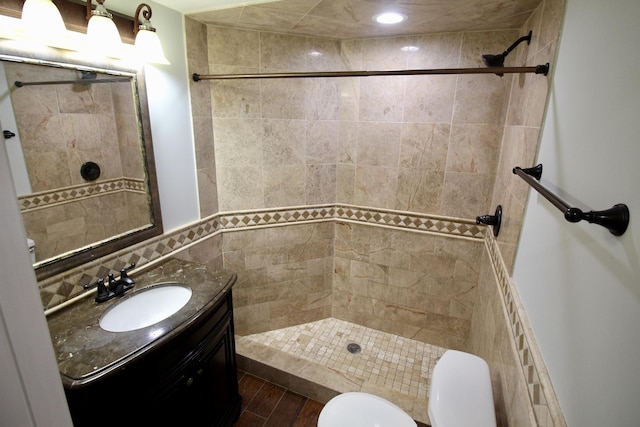 bathroom with vanity, toilet, and a tile shower