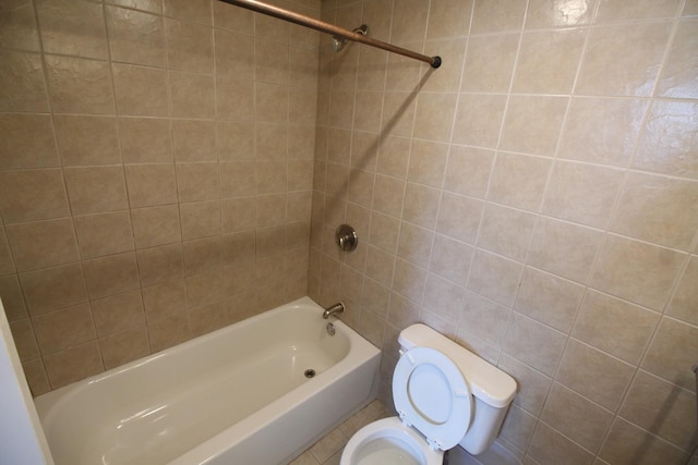 bathroom with toilet and tiled shower / bath combo