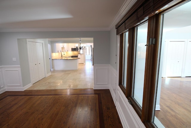 hallway featuring an inviting chandelier, light hardwood / wood-style flooring, and ornamental molding