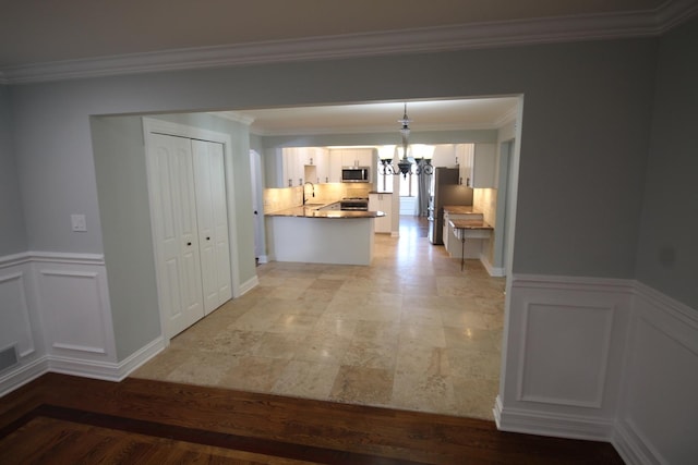 hall featuring ornamental molding, sink, and an inviting chandelier