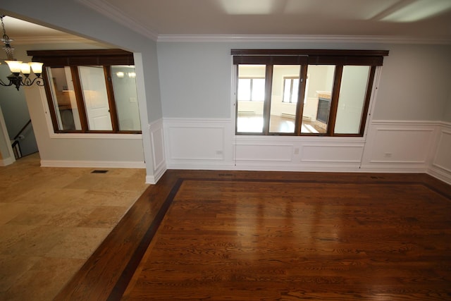 spare room with dark hardwood / wood-style flooring, ornamental molding, and a chandelier