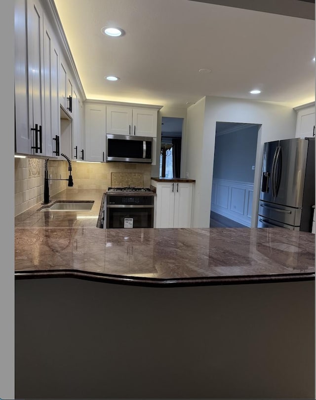 kitchen featuring stainless steel appliances, white cabinetry, and kitchen peninsula