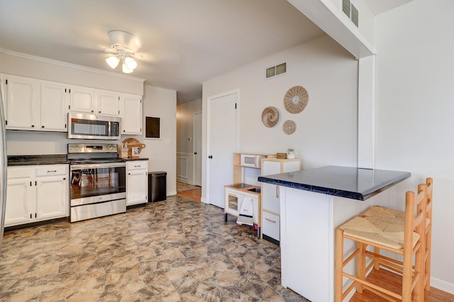 kitchen with white cabinets, a breakfast bar, ceiling fan, and appliances with stainless steel finishes