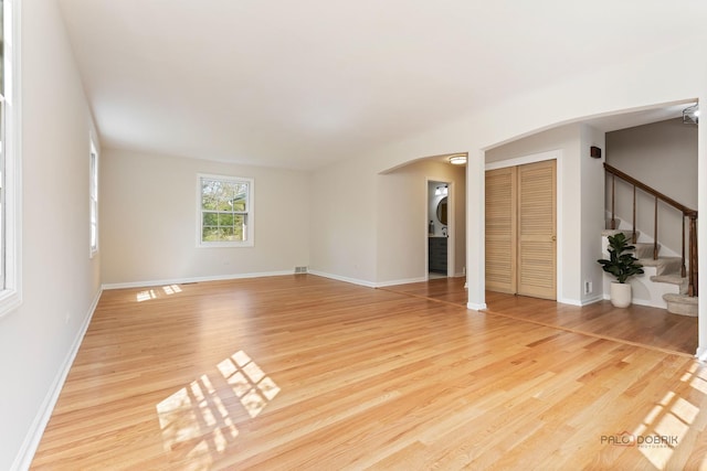 1712 Shawnee Trl, Northbrook, IL 60062 - unfurnished living room featuring arched walkways, light wood-style flooring, stairs, and baseboards