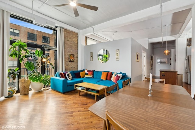 interior space featuring ceiling fan, hardwood / wood-style floors, and brick wall