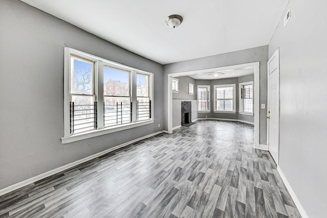 unfurnished living room with a brick fireplace, ceiling fan, and hardwood / wood-style flooring