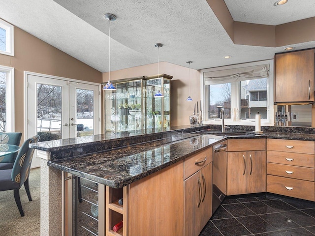 kitchen featuring a textured ceiling, a healthy amount of sunlight, decorative light fixtures, french doors, and dark stone countertops