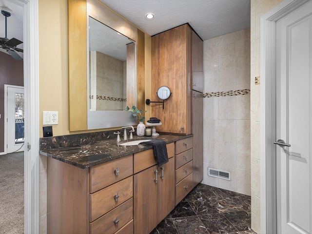 bathroom featuring tile walls, vanity, a textured ceiling, and ceiling fan