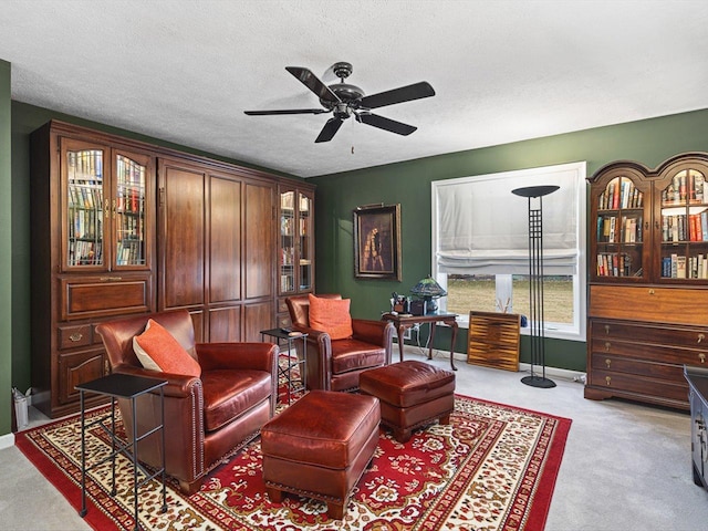 sitting room featuring ceiling fan, light carpet, and a textured ceiling