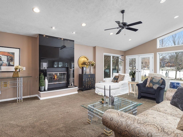 carpeted living room with vaulted ceiling, ceiling fan, french doors, a fireplace, and a textured ceiling