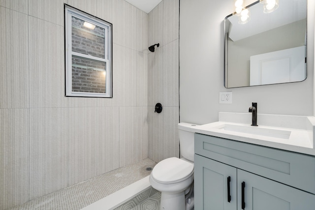 bathroom featuring toilet, a tile shower, and vanity