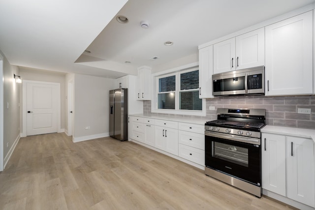 kitchen with stainless steel appliances, decorative backsplash, white cabinetry, and light wood-type flooring