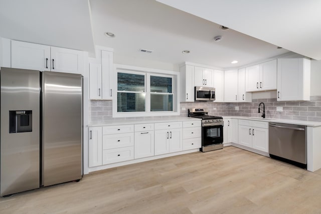 kitchen with stainless steel appliances, light hardwood / wood-style floors, decorative backsplash, white cabinets, and sink