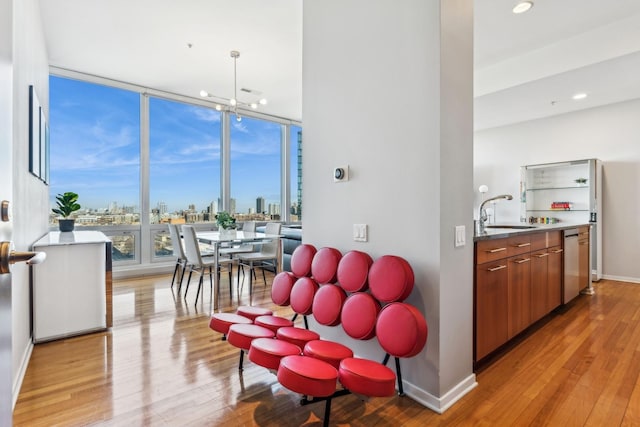 dining area featuring a notable chandelier, a wall of windows, sink, and light hardwood / wood-style flooring