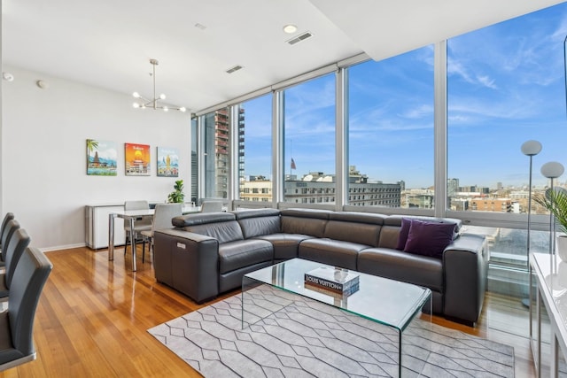 living room featuring hardwood / wood-style floors, a wall of windows, and an inviting chandelier