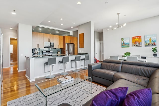 living room with light hardwood / wood-style flooring, a chandelier, and sink