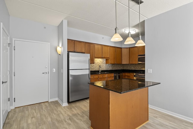 kitchen featuring sink, decorative light fixtures, dark stone countertops, appliances with stainless steel finishes, and backsplash