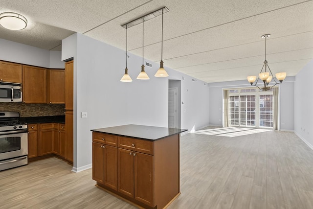 kitchen with decorative light fixtures, light hardwood / wood-style floors, decorative backsplash, and appliances with stainless steel finishes