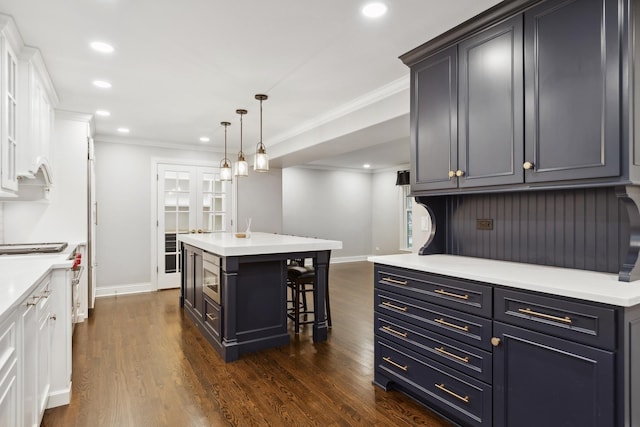 kitchen featuring dark wood-style floors, recessed lighting, crown molding, and a kitchen bar