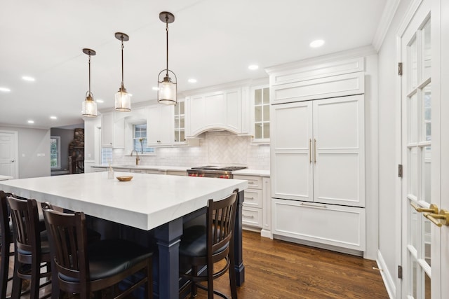 kitchen with built in fridge, dark wood-type flooring, backsplash, and white cabinetry