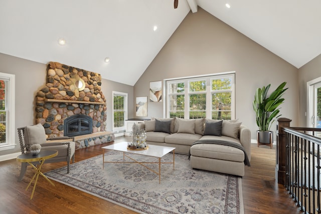 living room featuring high vaulted ceiling, a stone fireplace, wood finished floors, baseboards, and beam ceiling