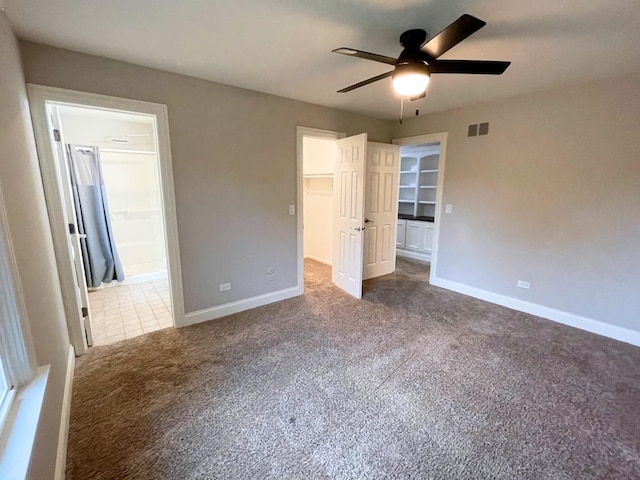 unfurnished bedroom with connected bathroom, carpet floors, visible vents, baseboards, and a walk in closet